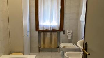 Une salle de bain équipée d’une baignoire, de toilettes, d’un bidet et d’un radiateur.
