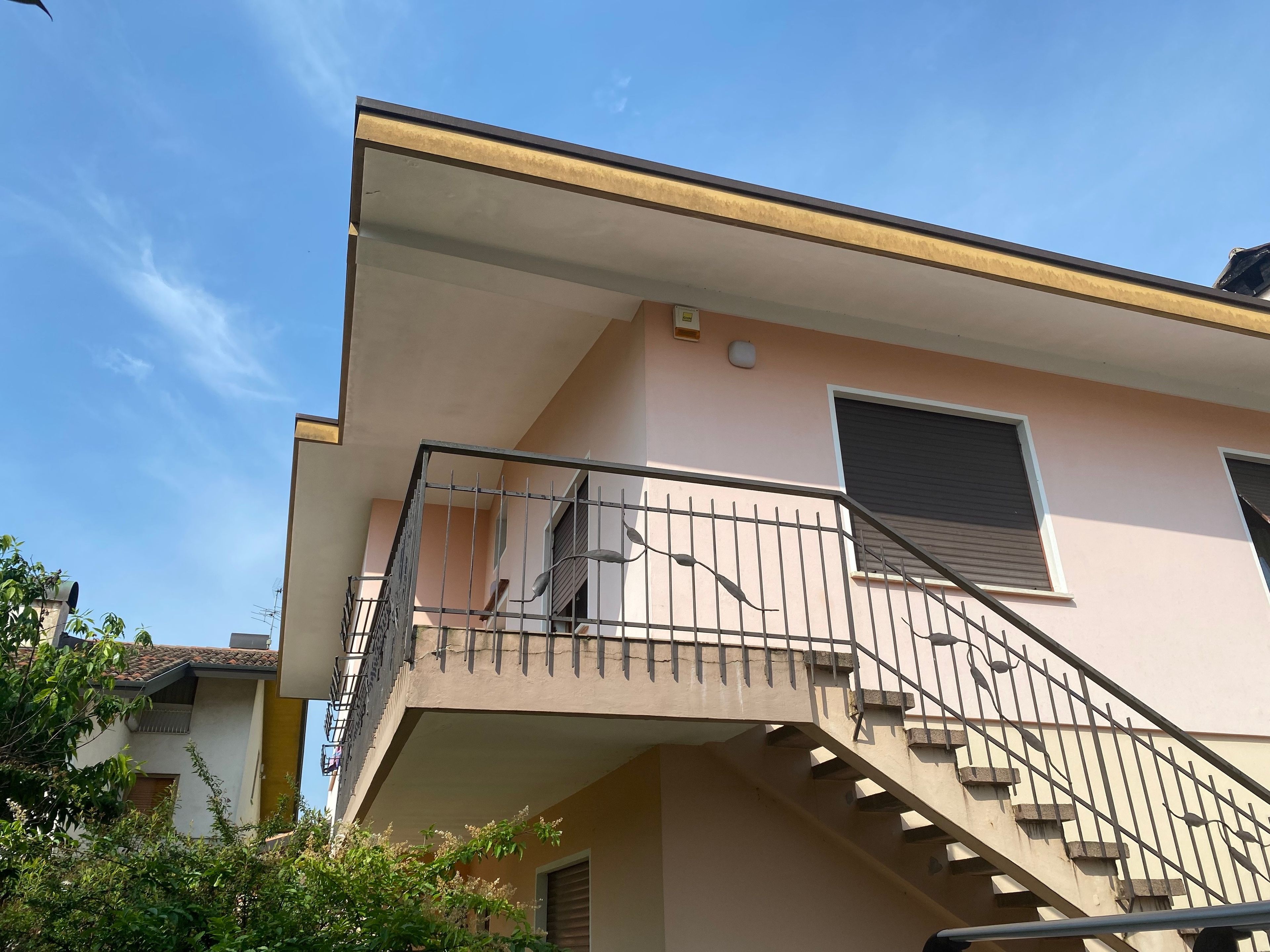 Ein Gebäude mit Balkon, Treppe und einem Fenster mit Rollläden.
