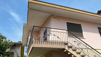 Ein Gebäude mit Balkon, Treppe und einem Fenster mit Rollläden.
