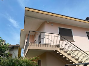 Un edificio con balcón, escalera y ventana con persianas.