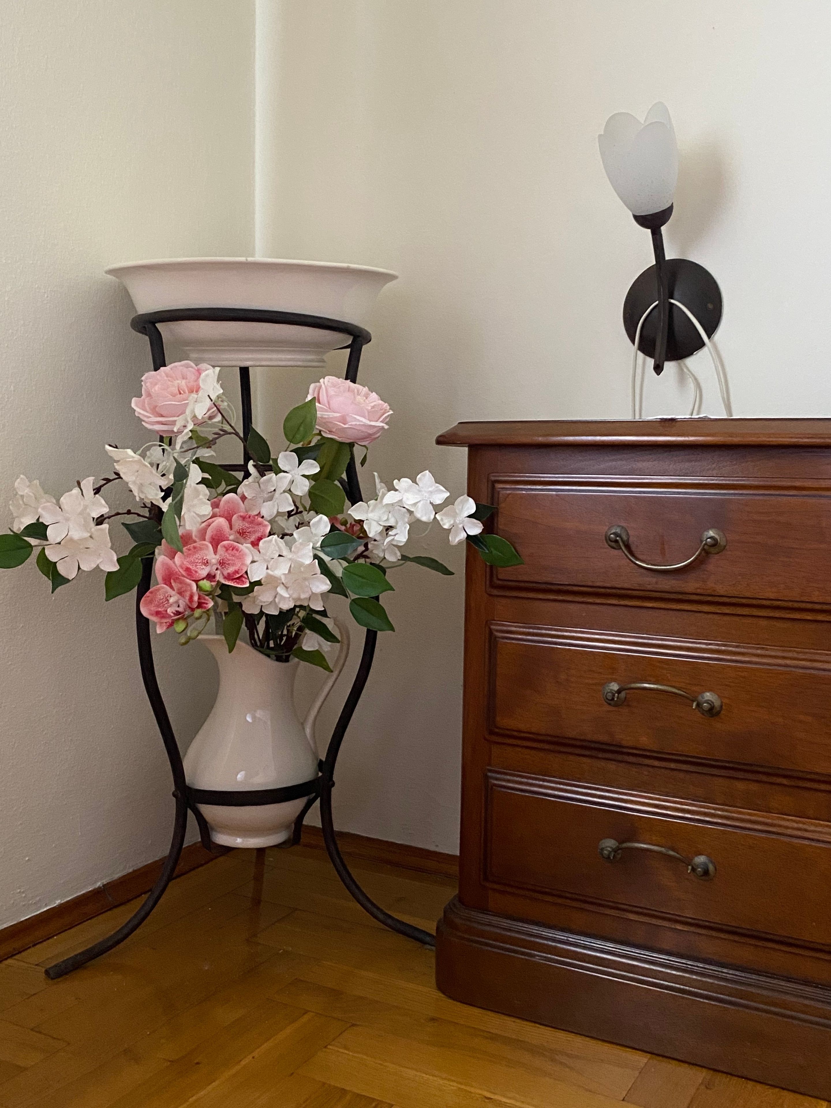 Eine hölzerne Kommode mit zwei Schubladen und eine Vase mit rosa und weißen Blumen.