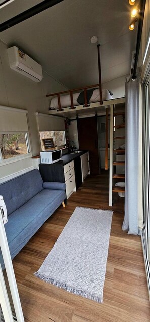 A compact living space with a sofa, a kitchen area, and a small dining table.