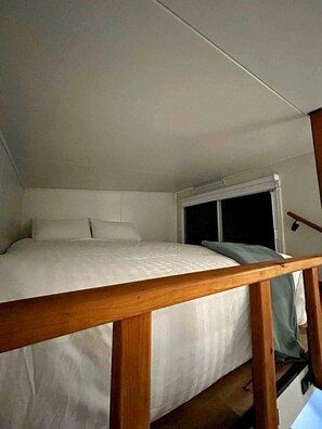A single bed with a wooden headboard in a room with a window.