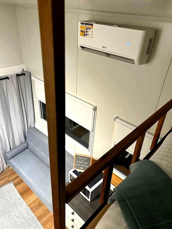 A compact room with a grey sofa, a small table, and a wooden staircase.