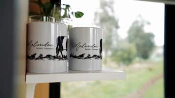 Two white mugs with black text and a silhouette design on a shelf by a window.