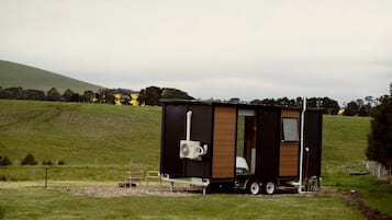 A mobile home with a small attached trailer, a window, and a power outlet.
