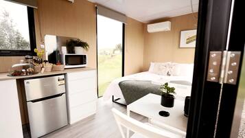 A modern bedroom with a bed, bedside table, and a view of the outdoors.