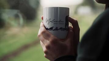 Una persona sosteniendo una taza con un diseño de paisaje.
