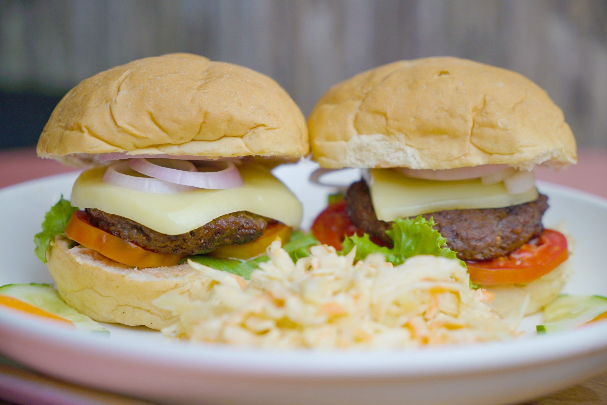 Dos hamburguesas con lechuga, tomate y queso, acompañadas de una porción de ensalada de col.