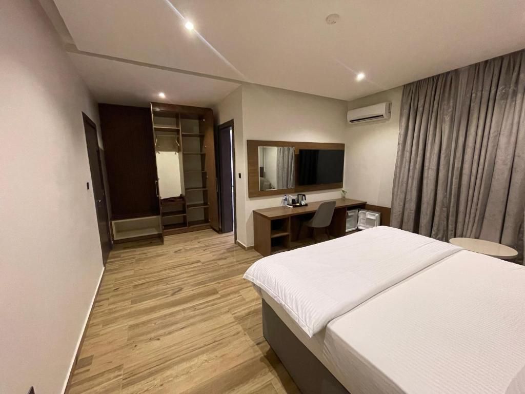 Una habitación de hotel con cama, escritorio, silla y armario.