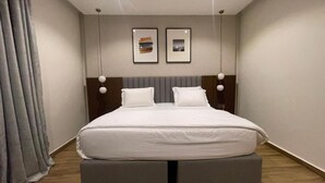 A modern bedroom with a bed, two bedside tables, and a headboard. - Paris Arena Holiday Inn (Abuja)