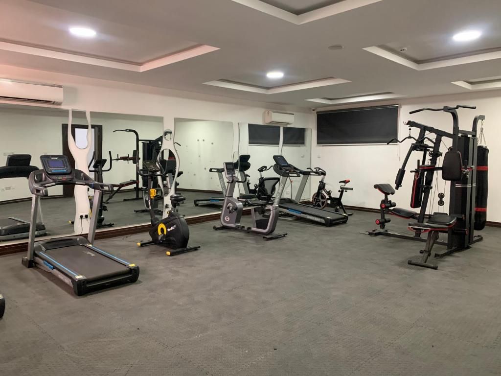 Un gimnasio con diverso equipo de ejercicio, incluyendo cintas de correr, bicicletas estáticas y máquinas de pesas.