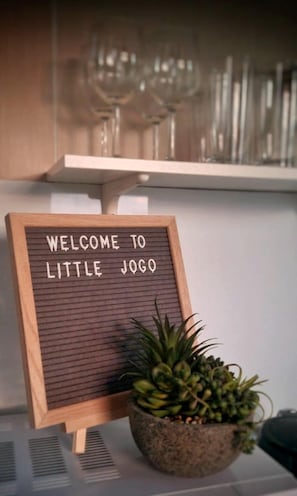 A welcome sign with a wooden frame and a small potted plant beside it.