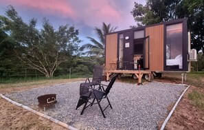 A small, single-story cabin with a deck, a table, and chairs outside.