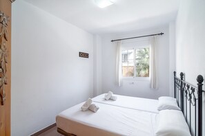 Ein Hotelzimmer mit zwei Betten, einem fensterbelaubten Fenster und einer kleinen Wanduhr.