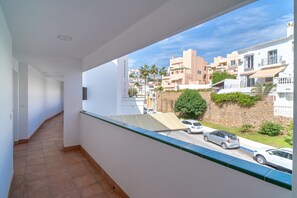 Ein Balkon mit Blick auf eine Wohnstraße, ein Solarpanel und eine Steinmauer.
