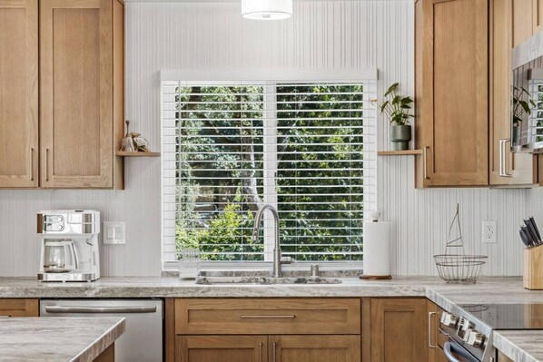 A kitchen with wooden cabinets, a built-in stove, a sink, and a window with blinds.