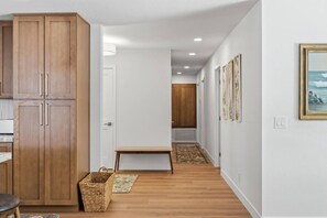 A hallway with wooden cabinets, a bench, and artwork on the walls.