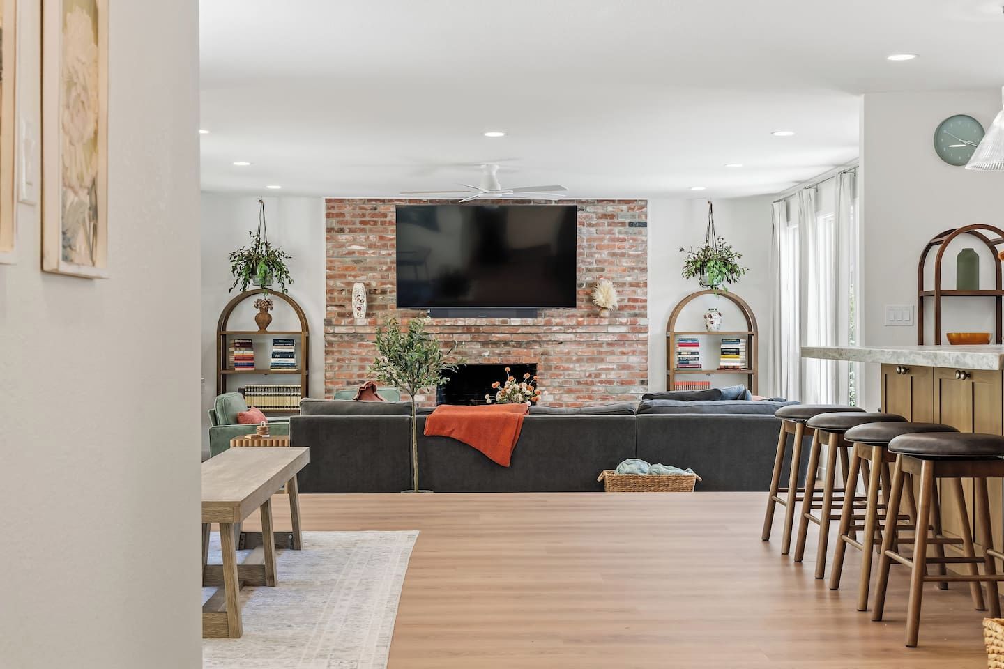 Een moderne woonkamer met een bakstenen open haard, een flatscreen televisie, een eethoek met een houten tafel en een bar met krukken.