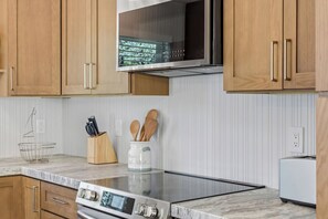 A modern kitchen with wooden cabinets, a stainless steel range hood, a microwave, and a built-in oven. - Stunning 4BR Estate | Secluded Folsom Getaway (Folsom)