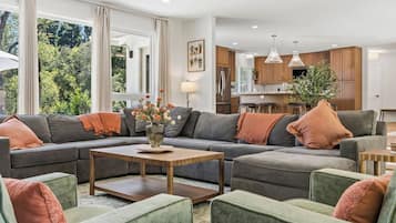 A modern living room with a sectional sofa, a coffee table, and a view of the kitchen.