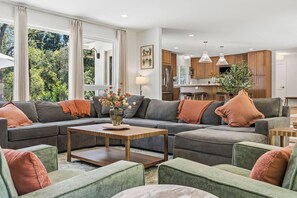 A modern living room with a sectional sofa, a coffee table, and a view of the kitchen.