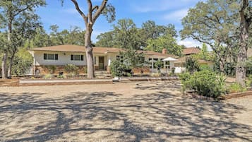 Una propiedad residencial con una casa de dos pisos, un porche cubierto y un jardín bien cuidado.