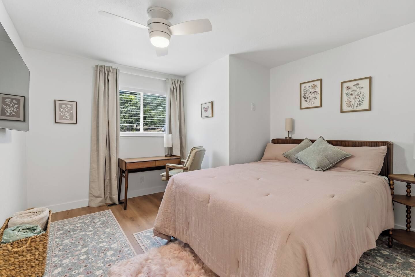 Een slaapkamer met een bed, bureau, stoel en plafondventilator.