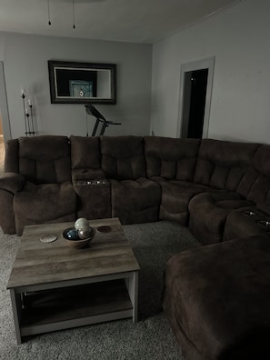Una sala de estar con un sofá modular, una mesa de centro y un cuadro en la pared.