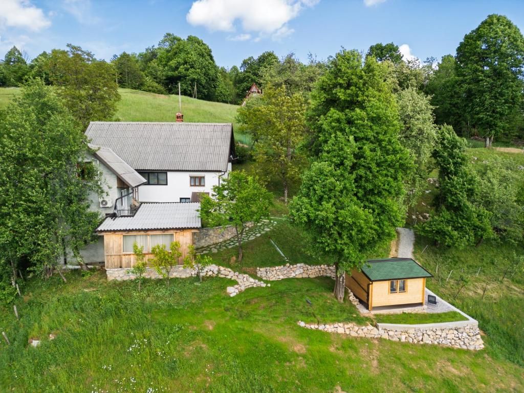 A two-story house with a sloped roof, surrounded by lush greenery and trees.