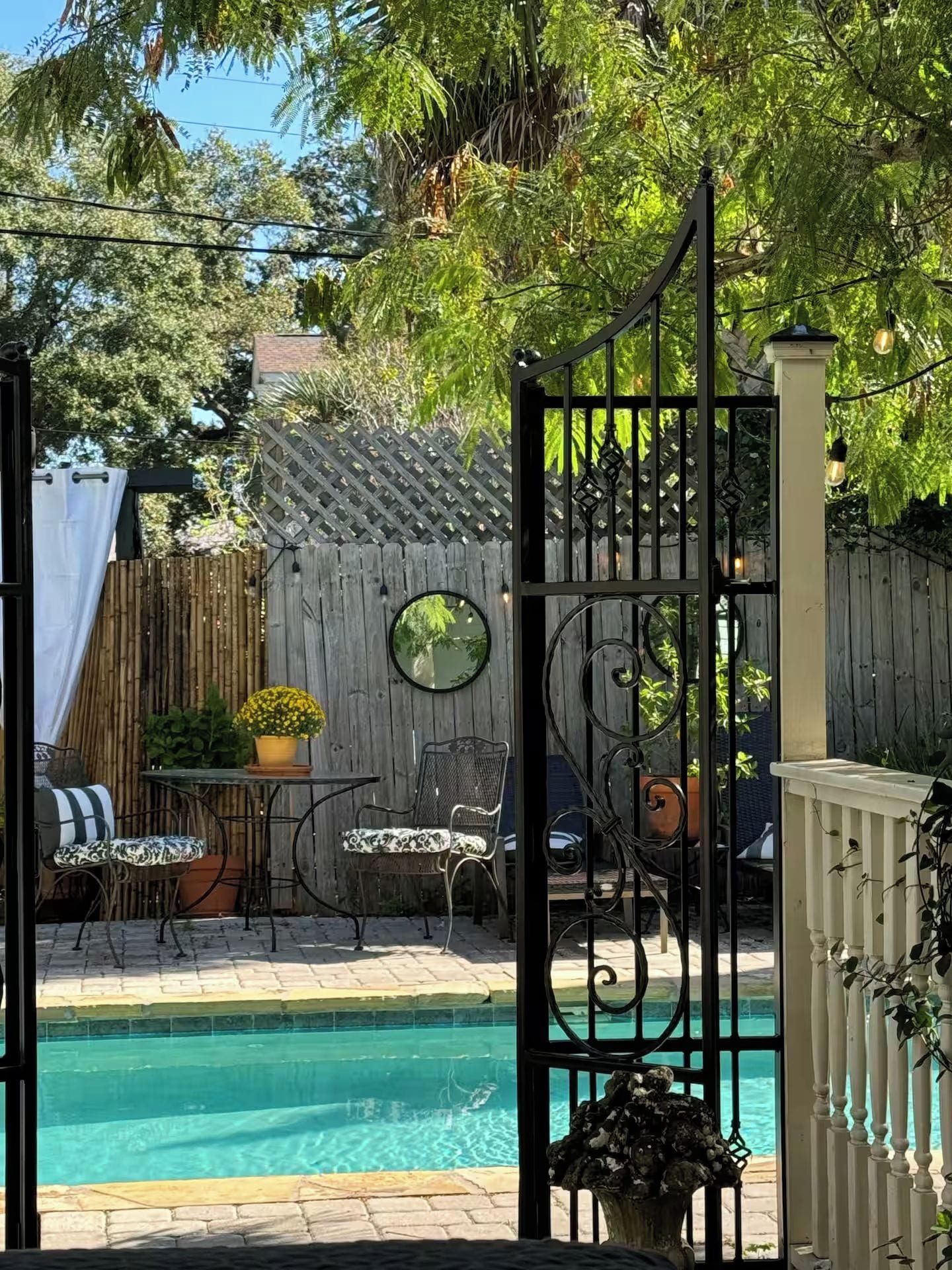 Un jardin avec une piscine, une clôture en bois et du mobilier d’extérieur.