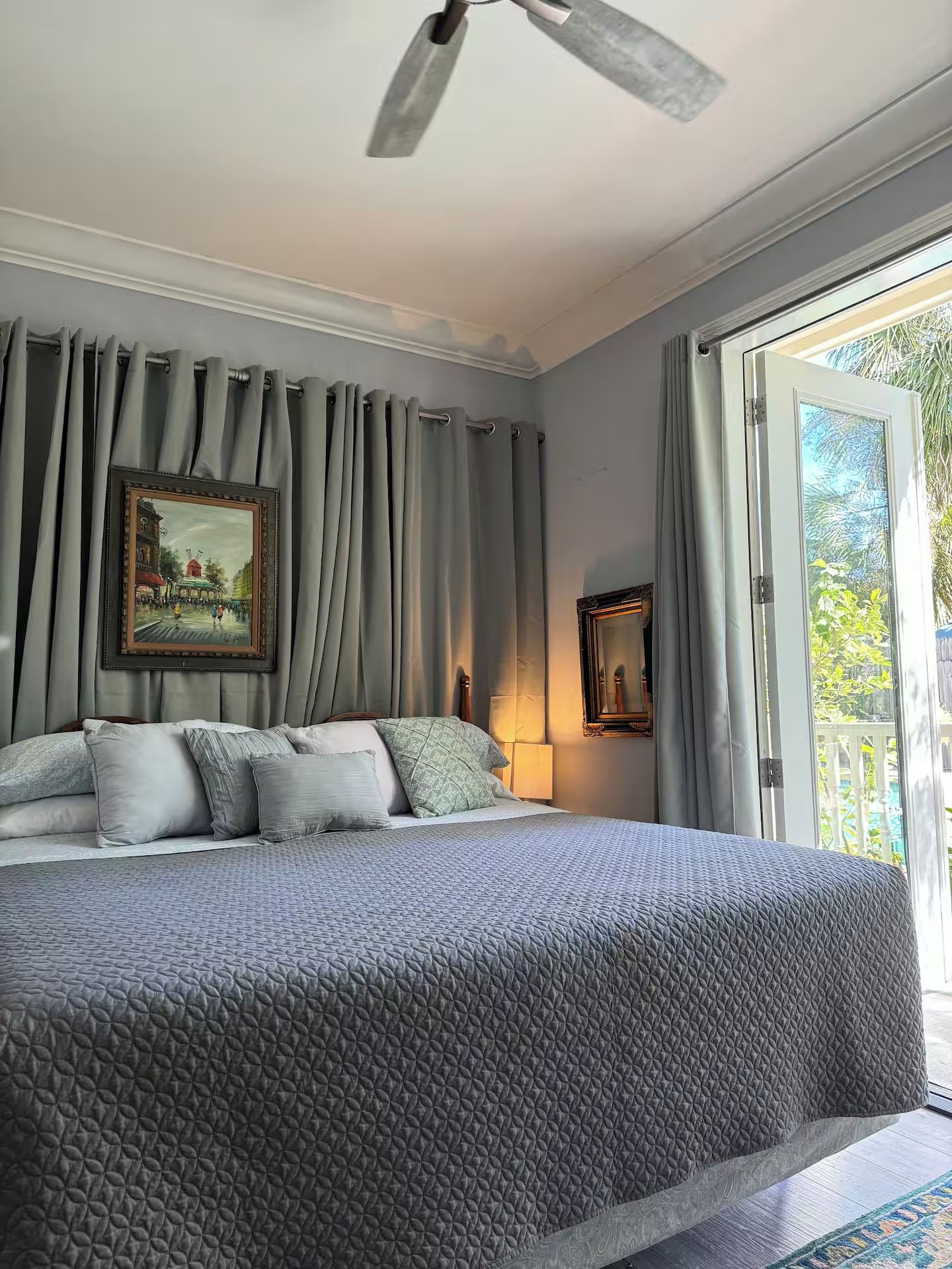 A bedroom with a large bed, two wall-mounted lamps, and a painting.
