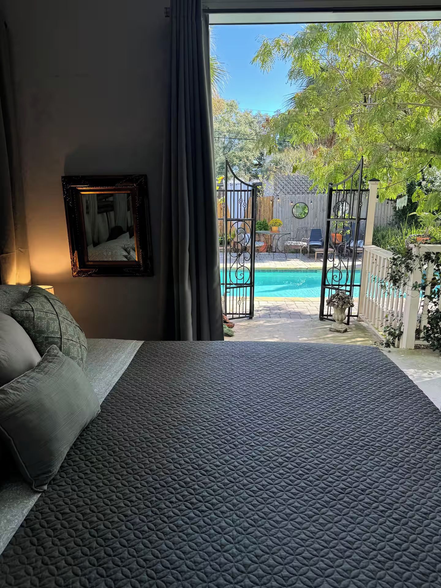 A bedroom with a view of a swimming pool through an open door.