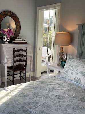 Une chambre à coucher avec un lit, un bureau, une chaise, une lampe et une fenêtre.
