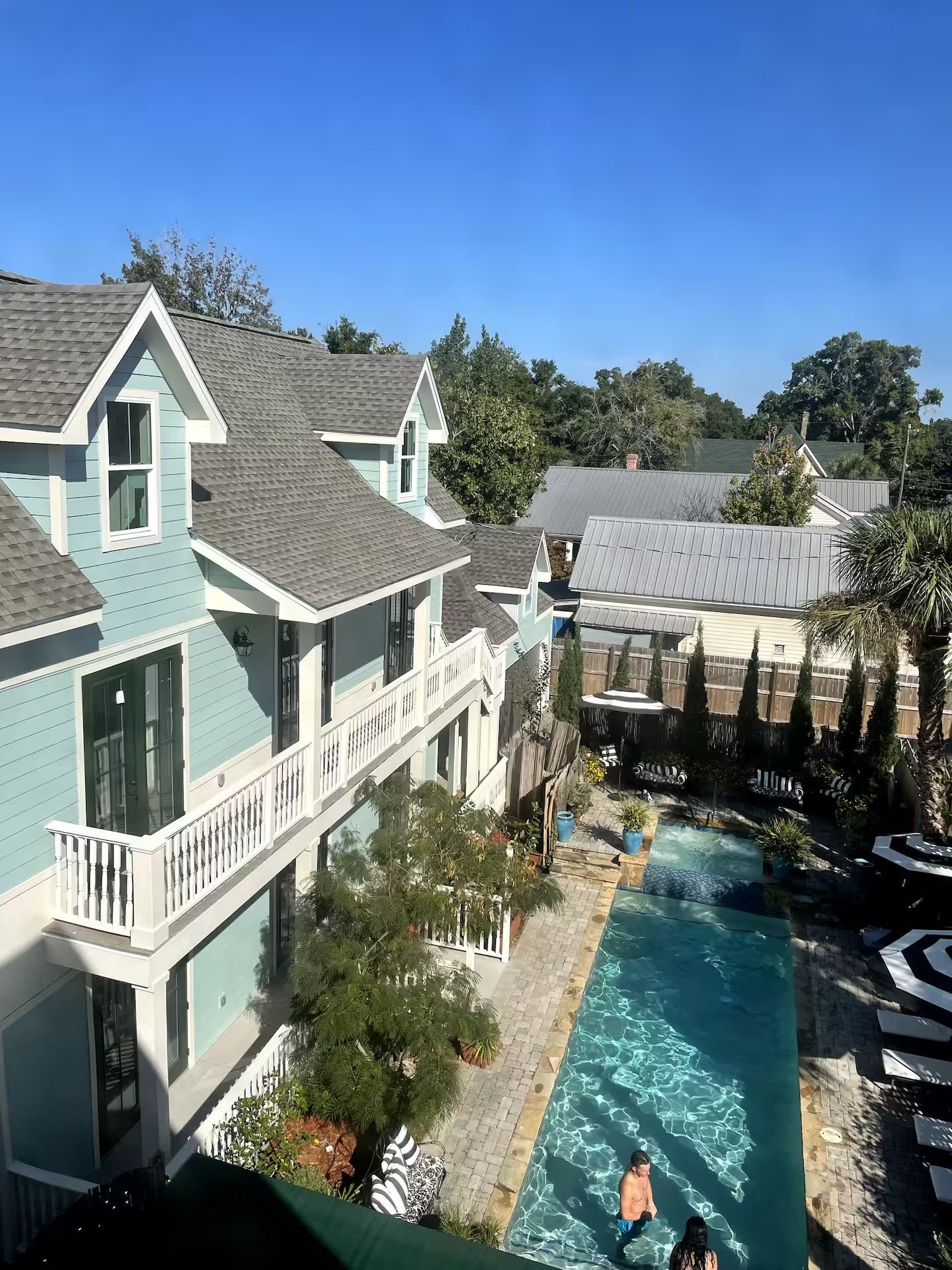 A residential property with a swimming pool, multiple balconies, and a view of surrounding trees.