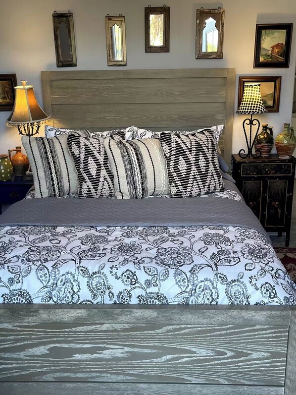 Een bed met beddengoed met een patroon, een houten hoofdbord en bedlampjes.