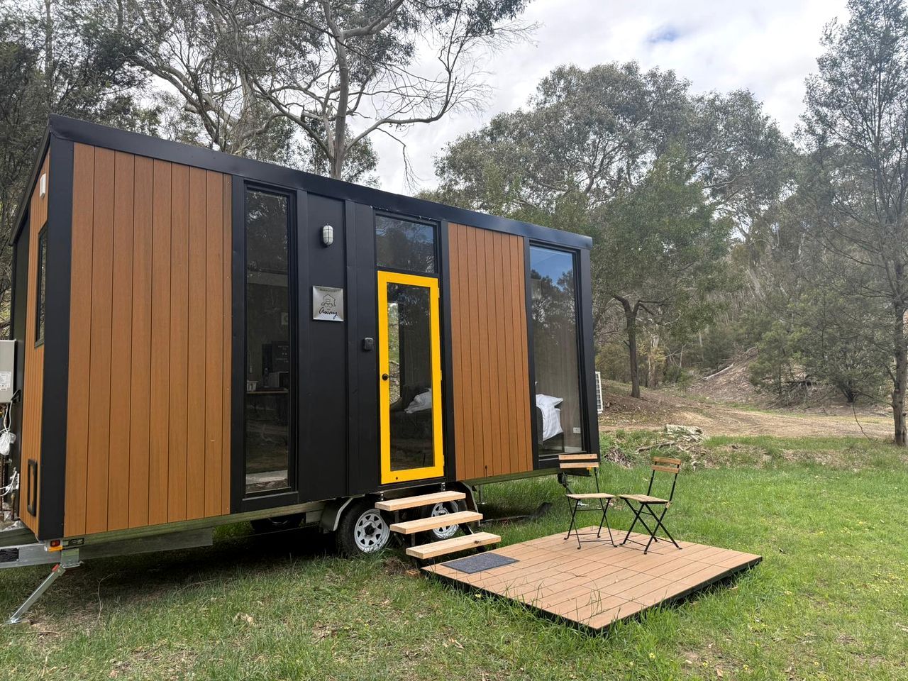 Una caravana moderna amb porta corredissa, un petit balcó i seients exteriors.