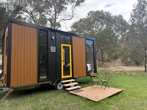 A modern mobile home with a sliding door, a small deck, and outdoor seating.