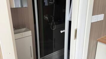 Une salle de bain avec une douche à parois de verre, un lavabo blanc et un miroir.