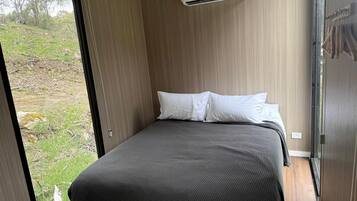 A bedroom with a bed, a window, and an air conditioning unit.