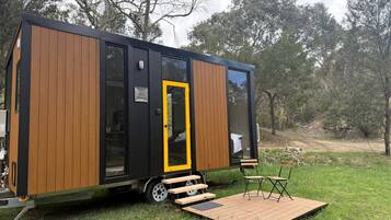 Une maison mobile moderne dotée d’une porte coulissante, d’une petite terrasse et d’un espace salon extérieur.