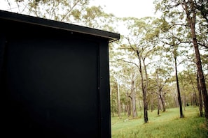 A black structure, possibly a shed or a small building, with a natural landscape in the background. - Cozy Tiny House with Bushland Views and Firepit in Mullaway, Australia (Mullaway)