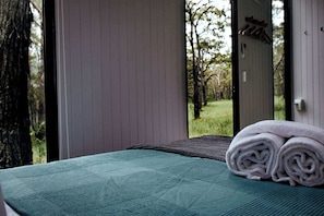 A room with a bed, a view of trees, and a door. - Cozy Tiny House with Bushland Views and Firepit in Mullaway, Australia (Mullaway)