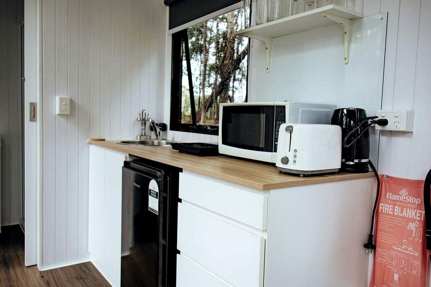 Een kleine keuken met een magnetron, broodrooster en koffiezetapparaat op een houten aanrecht.