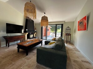 A living room with a fireplace, a sofa, a coffee table, and a television. - Peaceful Haven on the Banks of the Dordogne — Pool and Charm (Saint-Antoine-de-Breuilh)
