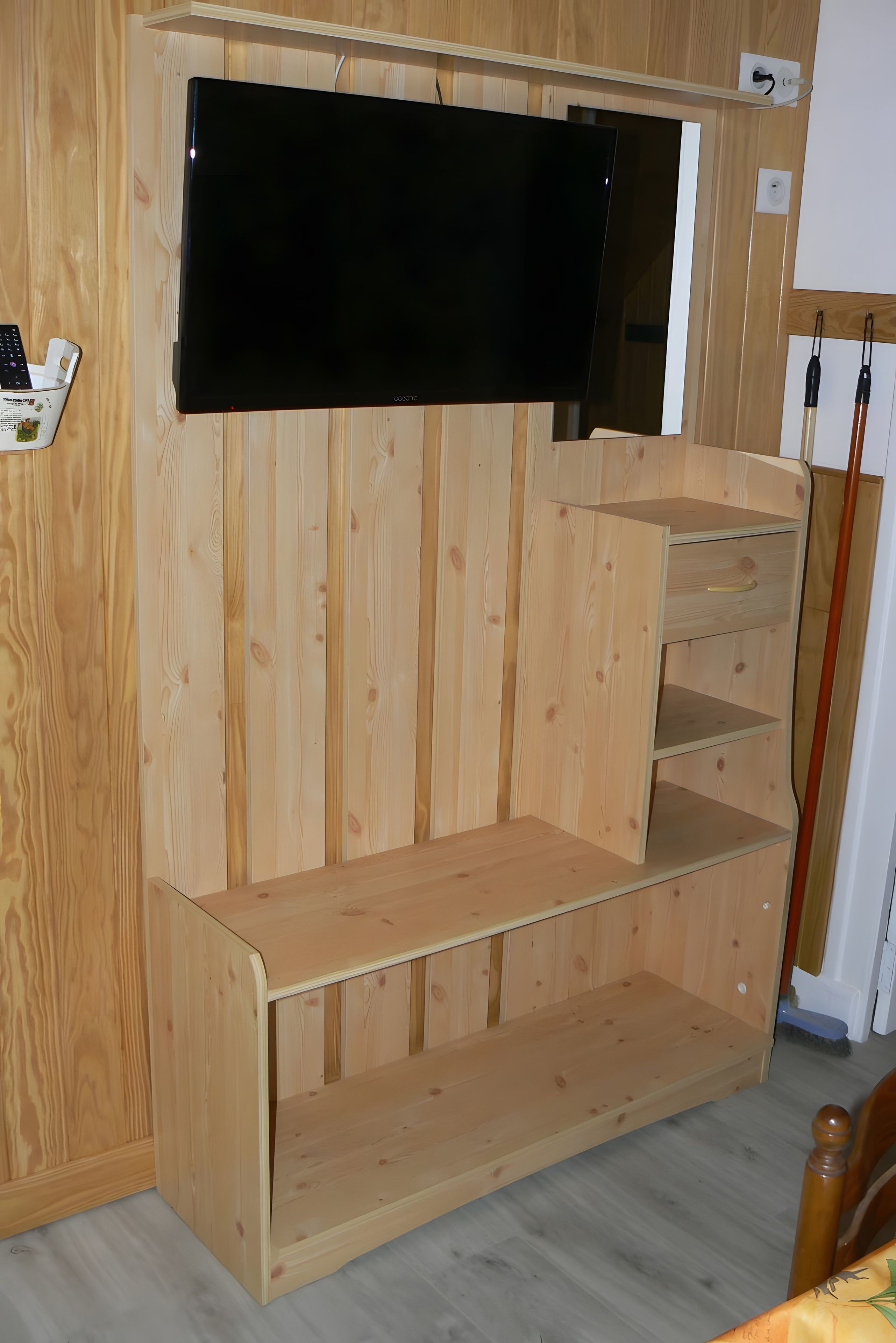 Un meuble de rangement en bois comprenant un téléviseur à écran plat, des étagères et une petite table.