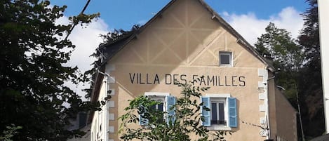 Un edificio con el letrero 'VILLA DES FAMILLES' y un estilo arquitectónico tradicional con tejado a dos aguas y contraventanas.