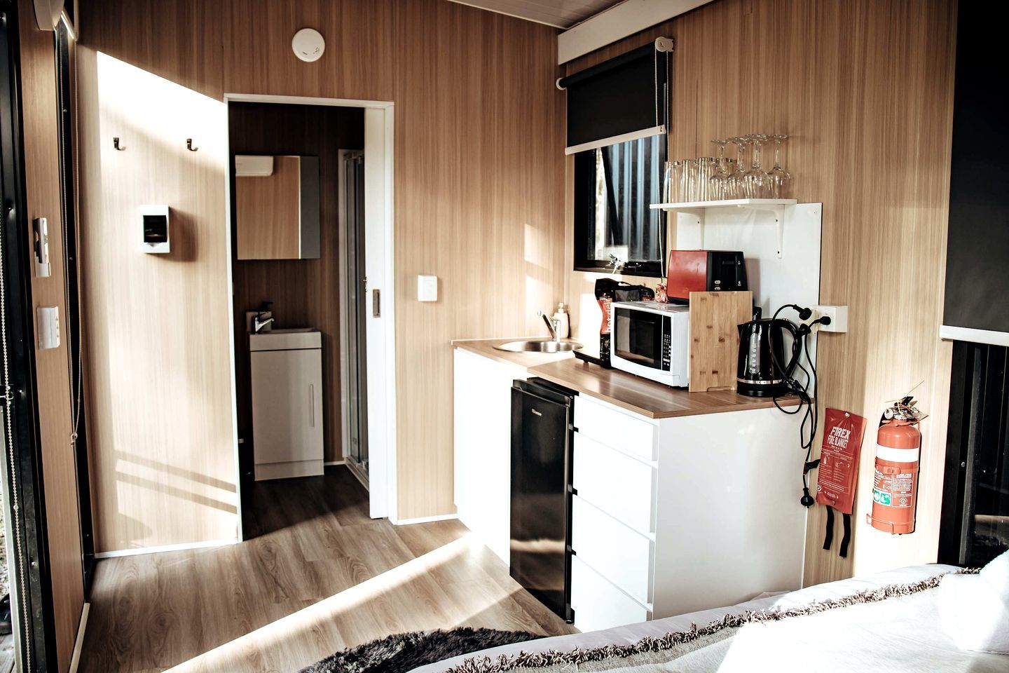 Een compacte hotelkamer met een kitchenette, een bed en een kleine badkamer.