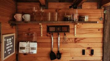 A wooden interior with a shelf holding glasses and jars, a clock, and a sign offering free samples.