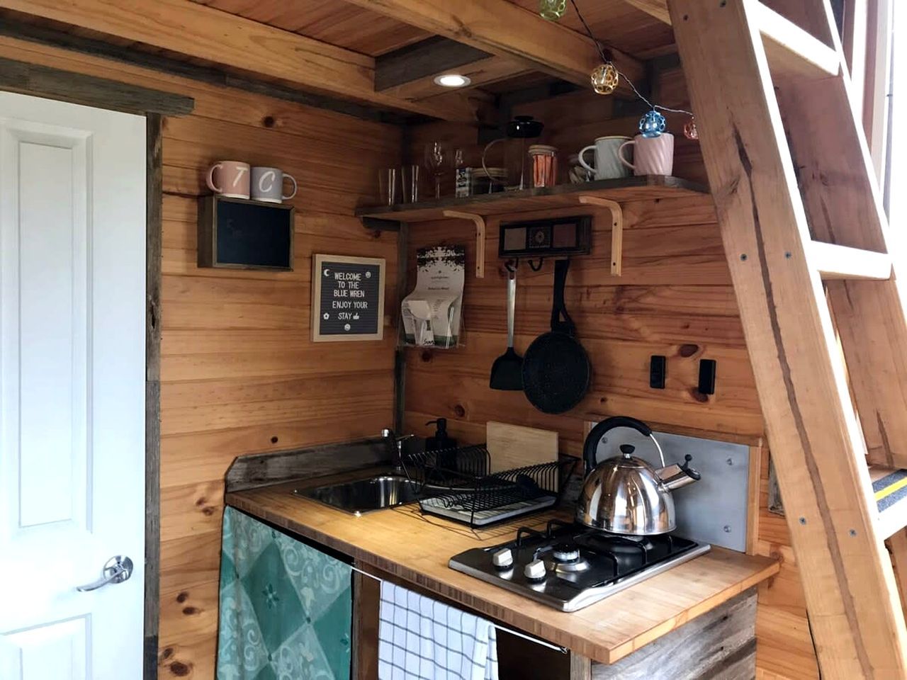 Une cuisine de taille réduite, équipée d’un évier, d’une cuisinière et d’ustensiles suspendus.